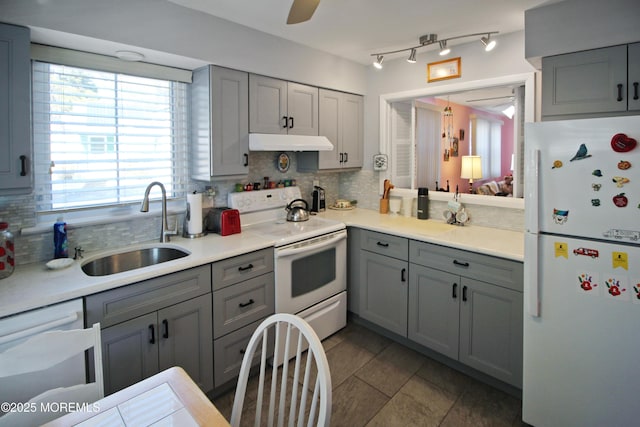 kitchen featuring tasteful backsplash, white appliances, sink, light tile patterned floors, and gray cabinets