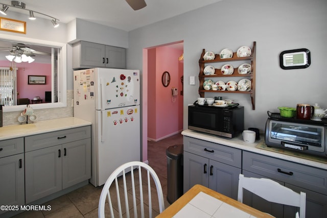 kitchen featuring decorative backsplash, white fridge, gray cabinets, and ceiling fan