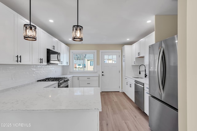 kitchen with appliances with stainless steel finishes, white cabinetry, decorative light fixtures, and sink