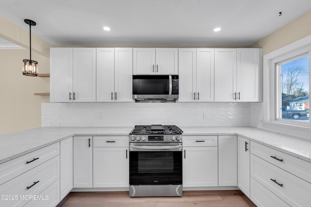 kitchen featuring light stone counters, decorative light fixtures, tasteful backsplash, white cabinetry, and appliances with stainless steel finishes