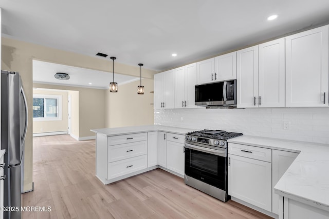 kitchen with kitchen peninsula, white cabinets, appliances with stainless steel finishes, and pendant lighting