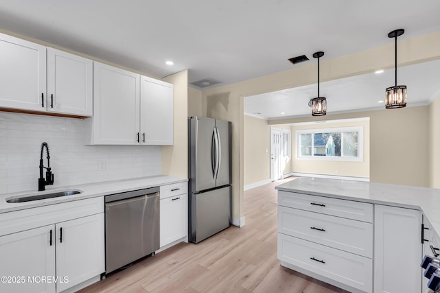 kitchen with appliances with stainless steel finishes, pendant lighting, white cabinetry, and sink