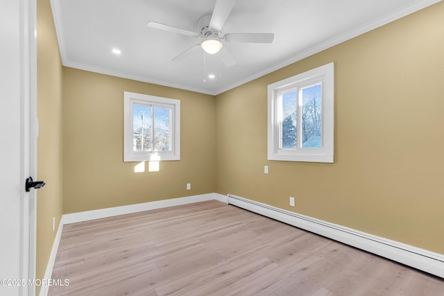 spare room with a baseboard radiator, light wood-type flooring, a wealth of natural light, and ornamental molding