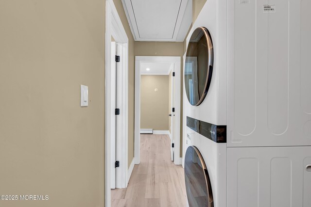 clothes washing area featuring stacked washer and clothes dryer and light hardwood / wood-style floors