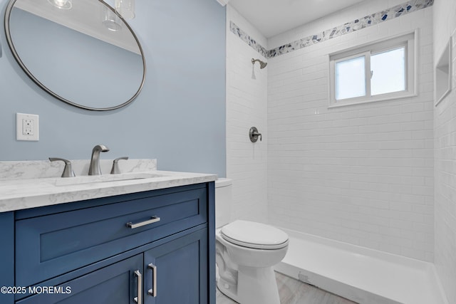 bathroom featuring toilet, wood-type flooring, vanity, and tiled shower