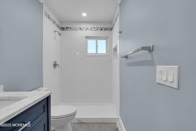 bathroom with a baseboard radiator, a tile shower, vanity, and toilet