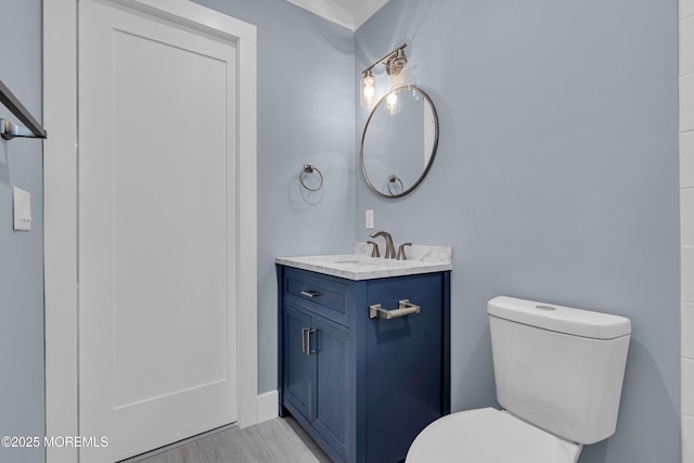 bathroom with crown molding, vanity, and toilet