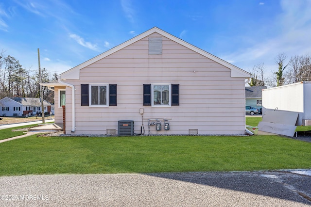 view of side of home with a yard and central AC