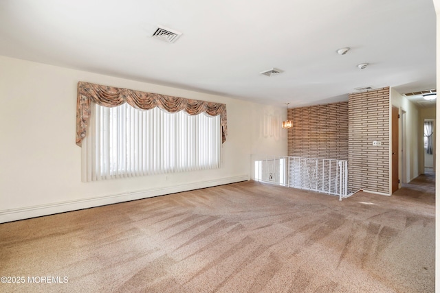 carpeted empty room featuring baseboard heating and an inviting chandelier