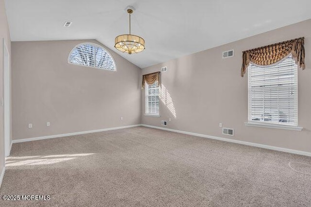 carpeted empty room with a healthy amount of sunlight and lofted ceiling