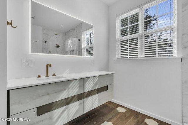 bathroom featuring a shower with shower door and vanity