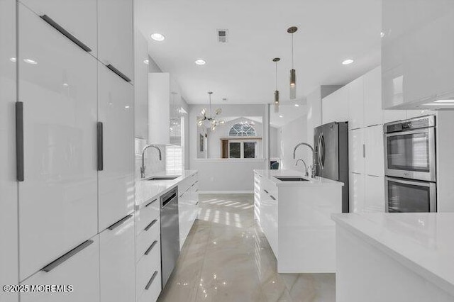 kitchen with decorative light fixtures, sink, white cabinets, and stainless steel appliances