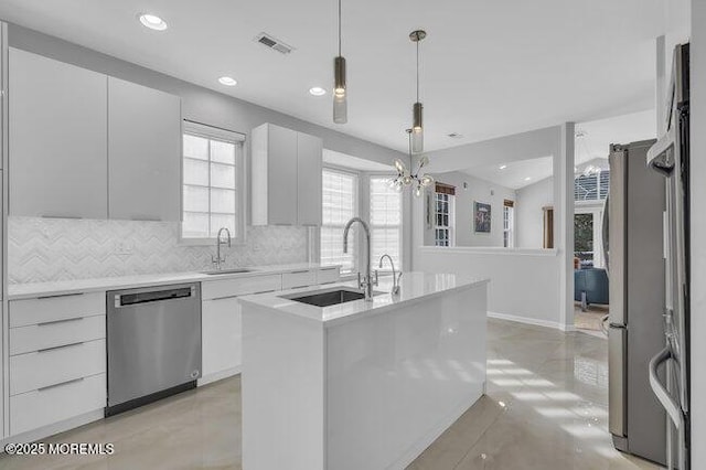 kitchen with white cabinets, a kitchen island with sink, pendant lighting, and appliances with stainless steel finishes