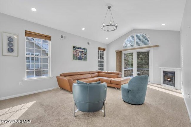 living room featuring a healthy amount of sunlight, an inviting chandelier, light colored carpet, and lofted ceiling