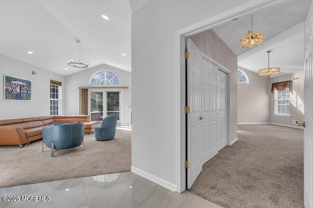 hall featuring light colored carpet, vaulted ceiling, and a notable chandelier