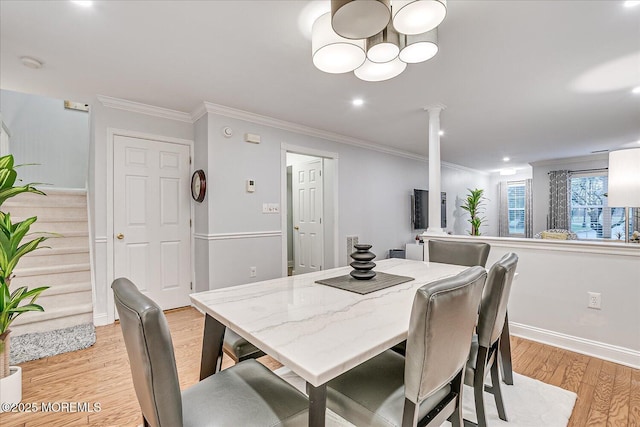 dining space with ornate columns, ornamental molding, and light hardwood / wood-style flooring