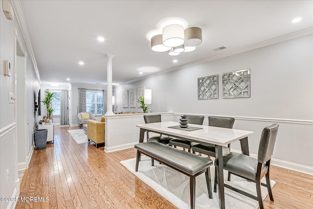 dining room with decorative columns, light hardwood / wood-style flooring, and crown molding