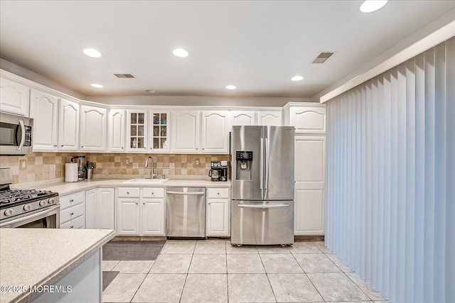 kitchen with sink, white cabinets, stainless steel appliances, and light tile patterned floors