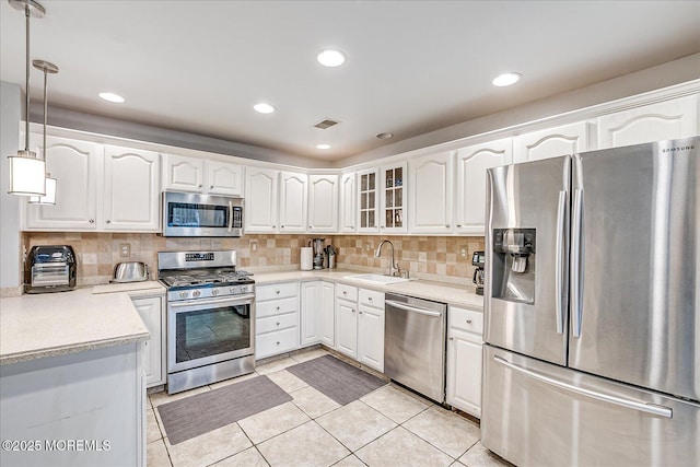 kitchen with decorative light fixtures, sink, white cabinetry, and stainless steel appliances