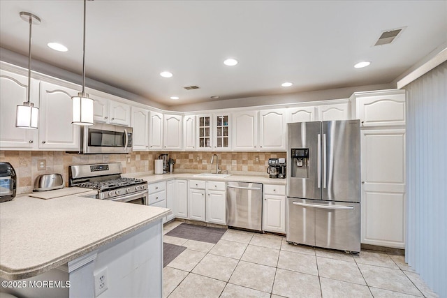 kitchen with light tile patterned floors, stainless steel appliances, white cabinetry, and hanging light fixtures