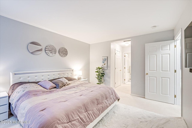 bedroom with ensuite bath and light colored carpet