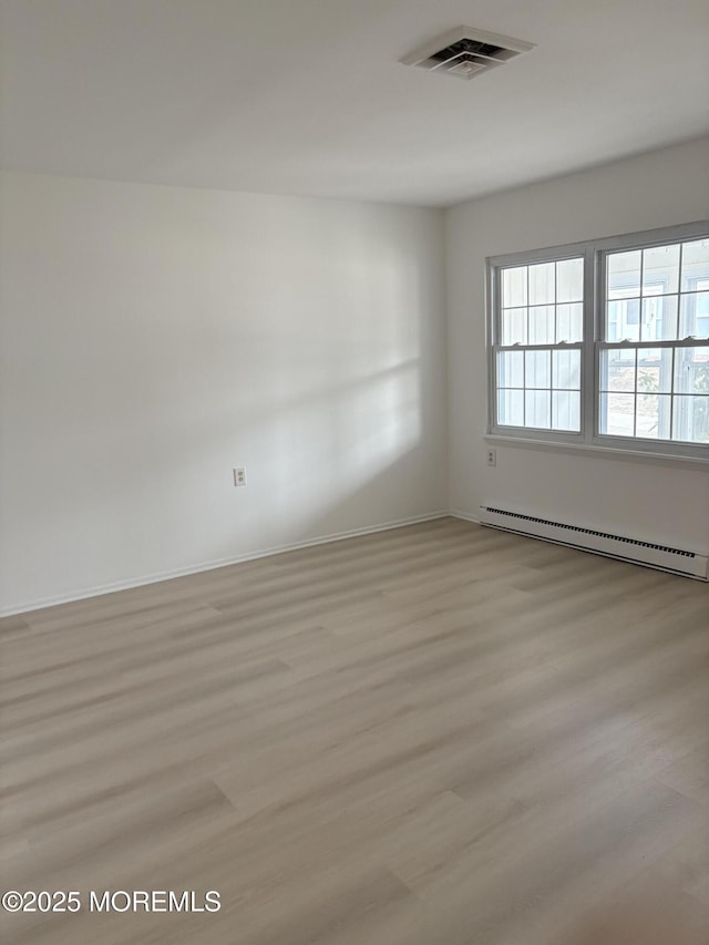 spare room with a baseboard radiator and light hardwood / wood-style flooring