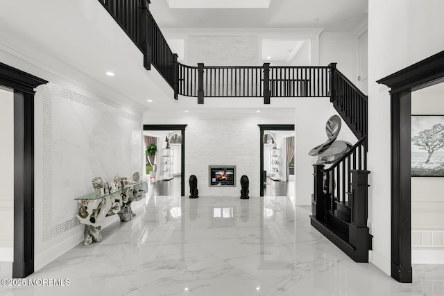 foyer featuring a high ceiling, a skylight, and crown molding