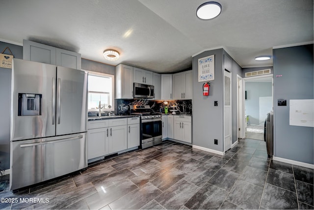 kitchen with decorative backsplash, a textured ceiling, stainless steel appliances, and lofted ceiling