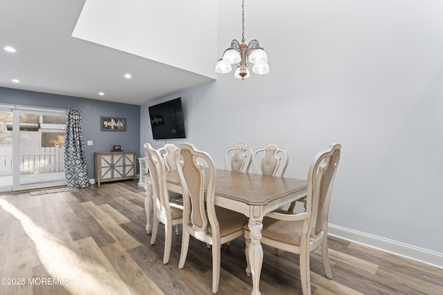 dining space with wood-type flooring and an inviting chandelier