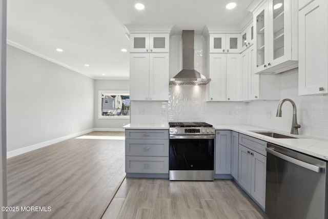 kitchen featuring appliances with stainless steel finishes, white cabinets, gray cabinets, and wall chimney exhaust hood