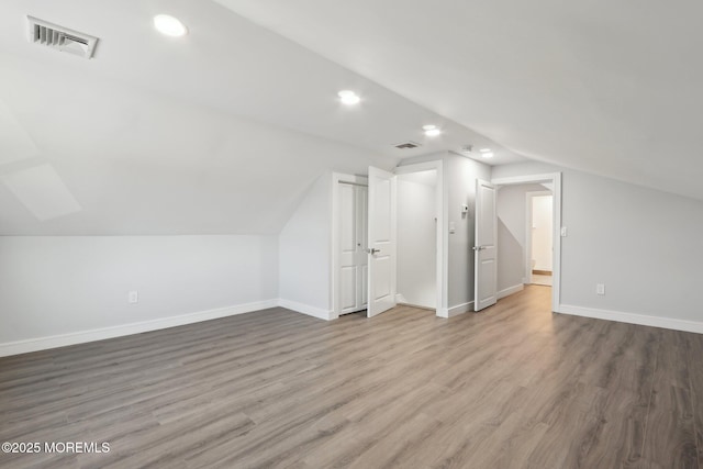 additional living space featuring light hardwood / wood-style flooring and vaulted ceiling