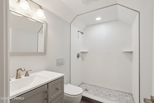 bathroom featuring tiled shower, vanity, and toilet