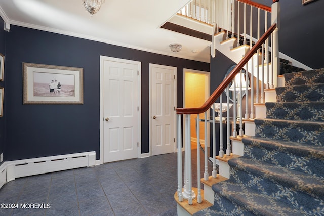 foyer with dark tile patterned floors, ornamental molding, and a baseboard heating unit