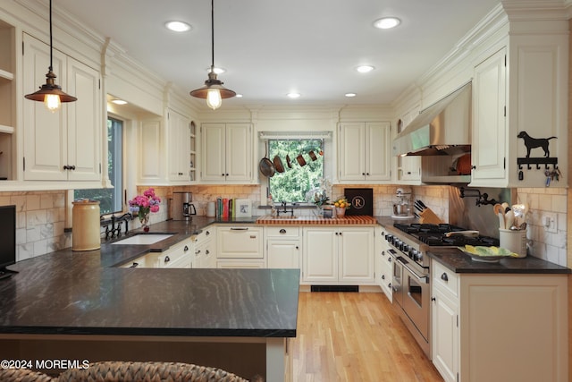 kitchen with kitchen peninsula, sink, decorative light fixtures, range with two ovens, and range hood