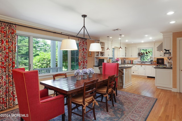 dining area with light hardwood / wood-style flooring and crown molding