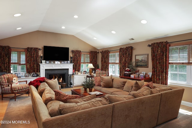 living room with plenty of natural light, light wood-type flooring, and vaulted ceiling