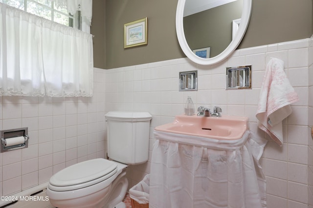 bathroom with toilet and tile walls