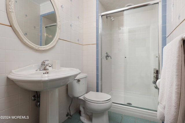 bathroom with toilet, a shower with door, and tile walls