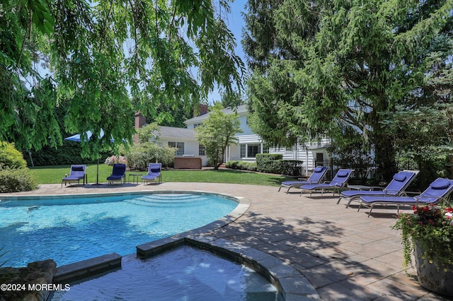 view of pool featuring an in ground hot tub, a yard, and a patio area