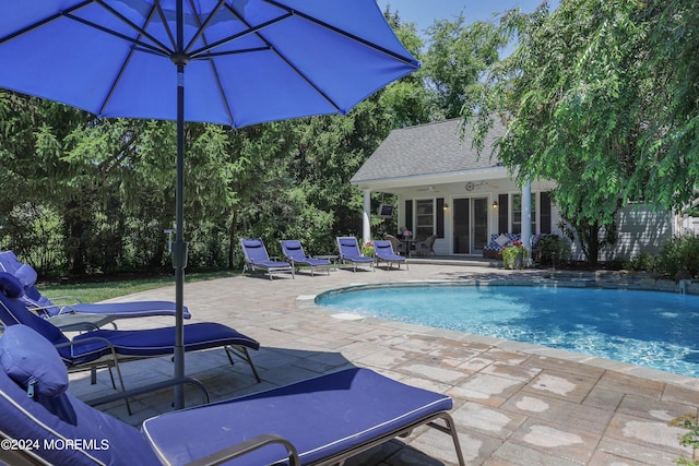 view of pool featuring an outbuilding, pool water feature, and a patio