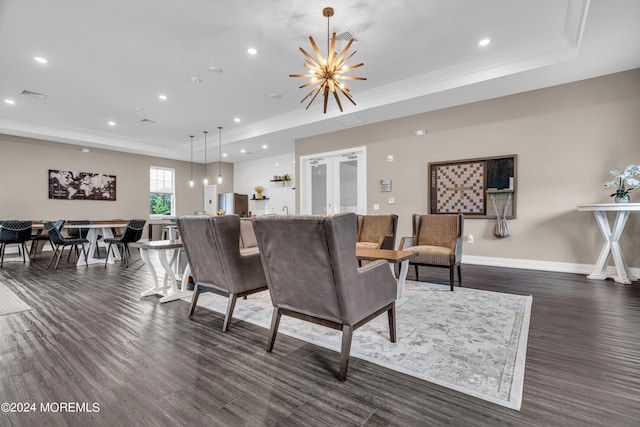 living room with a chandelier, ornamental molding, a tray ceiling, and dark wood-type flooring