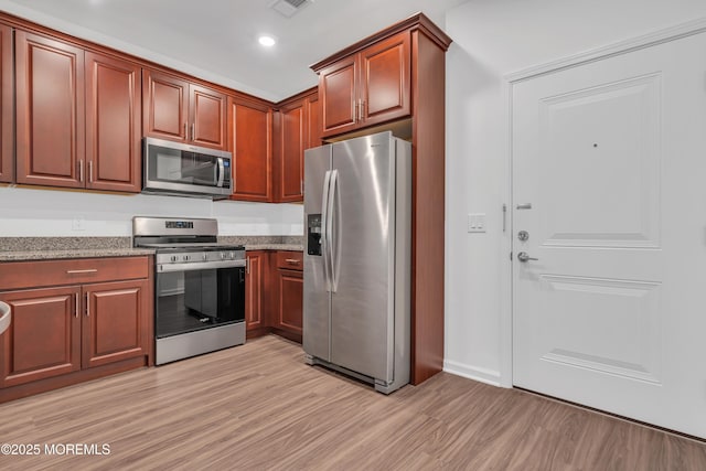 kitchen featuring stainless steel appliances, light hardwood / wood-style flooring, and stone countertops