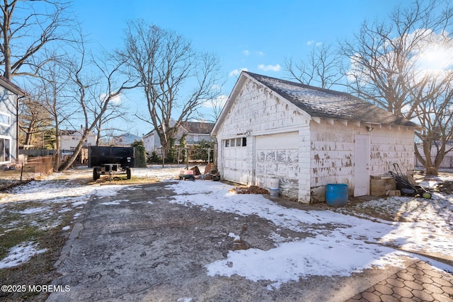 view of snowy exterior featuring an outdoor structure and a garage