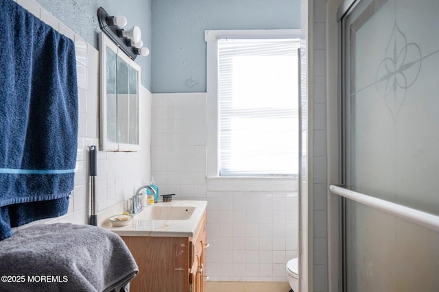 bathroom with vanity, toilet, tile walls, and walk in shower