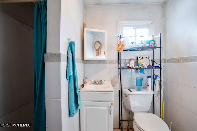 bathroom featuring vanity, tile walls, and toilet