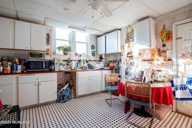 kitchen with white cabinetry, a drop ceiling, ceiling fan, and sink