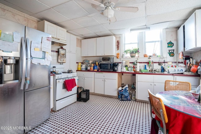 kitchen with a drop ceiling, white cabinets, stainless steel appliances, and sink