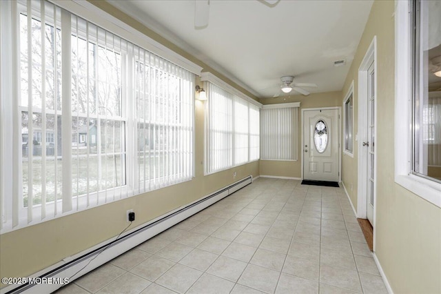 unfurnished sunroom with a wealth of natural light, ceiling fan, and a baseboard heating unit