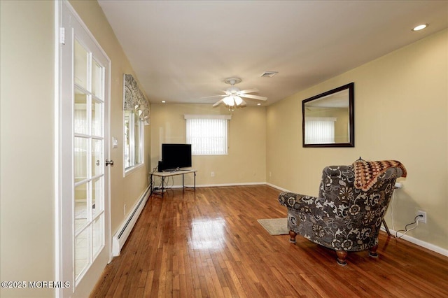 living area with ceiling fan, wood-type flooring, and baseboard heating