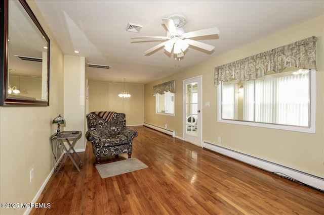 sitting room featuring wood-type flooring, ceiling fan with notable chandelier, and baseboard heating